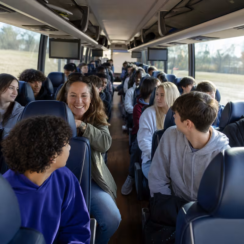 Group boarding a white charter bus for School Transportation transportation in Indianapolis